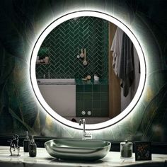 a bathroom sink under a round mirror in front of a green tiled wall and counter