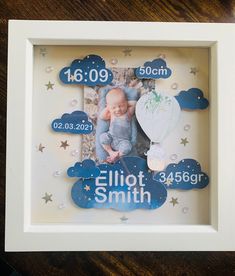 a baby's birth photo in a white frame with stars and clouds on it