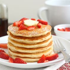 a stack of pancakes topped with butter and strawberries