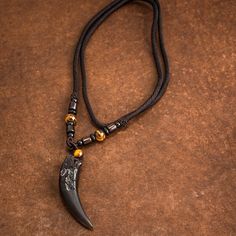 This dramatic looking pendant is made from natural stone and obsidian (volcanic glass) in the shape of a wolf's tooth. Wolf heads adorn either side. It's a statement piece that's great for everyday wear, or as a gift for someone who shares your love of wolves and will make an excellent addition to any wardrobe.. Available with rope or bead style chains. Pendant size approx - 63 x 14mm (2.5 x 0.5 inches). Chain length approx 60cm (23") Norse Jewelry Men, Mens Stone Necklace, Men Stone Necklace, Viking Necklace Men, Wolf Tooth Necklace, Viking Wolf, Wolf Tooth, Wolf Teeth, Vikings Gifts