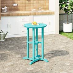 a small blue table sitting on top of a tiled floor next to a potted plant