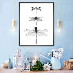 three dragonflys sitting on top of a table next to white flowers and candles