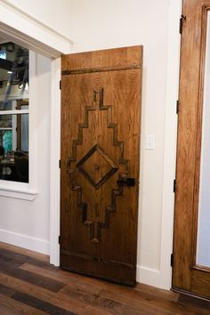 an old wooden door in the corner of a room with wood floors and white walls