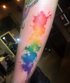 a person with a tattoo on their arm has a rainbow colored ink stain in the shape of a hand