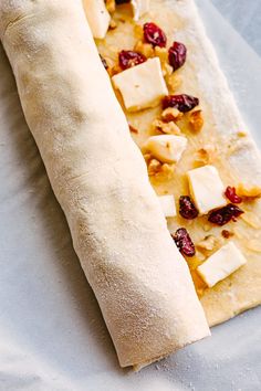 a long piece of bread with cheese and cranberries on it