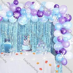 a table topped with balloons and cake next to a wall covered in snowflakes