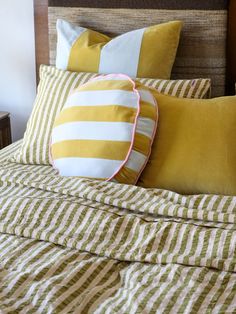 a bed with yellow and white striped pillows