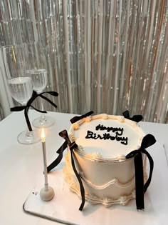 a birthday cake sitting on top of a table next to a wine glass and candle