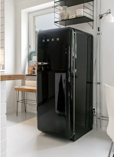 a black refrigerator sitting in the middle of a kitchen