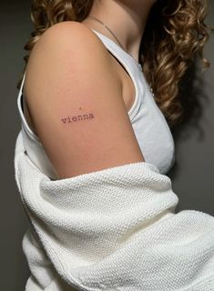 a woman with a small tattoo on her arm that reads, vitema in cursive writing