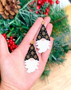 a hand holding two black and white beaded christmas decorations on it's fingers