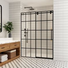 a bathroom with black and white tiles on the floor, sink, mirror and shower stall