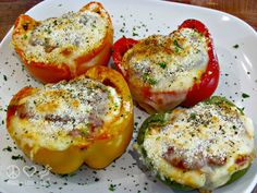 four stuffed peppers on a plate with parmesan cheese and seasoning sprinkles