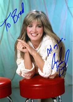 an autographed photo of a woman sitting on top of stools with her arms crossed