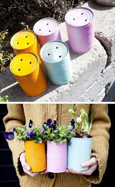 several different colored tin cans with flowers in them, and one is holding a potted plant