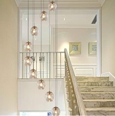 an elegant staircase with glass balls hanging from the handrail and marble steps leading up to the second floor