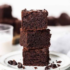 three brownies stacked on top of each other with chocolate chips and milk in the background