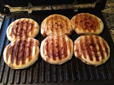 six pancakes are cooking on the grill in the kitchen with chocolate syrup drizzled over them