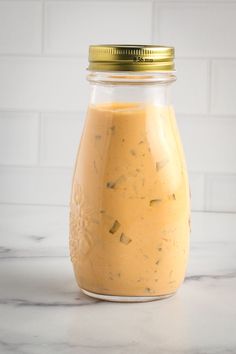 a glass jar filled with mustard sitting on top of a counter