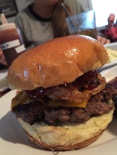 a hamburger with meat and cheese on it sitting on a plate