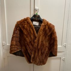 a brown fur coat hanging on a white door