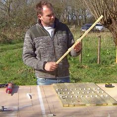 a man standing next to a piece of wood with a stick in it's hand