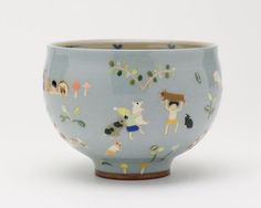 a blue bowl with animals and plants on it's sides, sitting in front of a white background