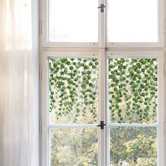 an open window with green leaves on it