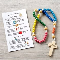 a wooden cross and beads with a card on the table next to it that says, my first rosary