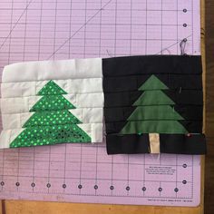 two pieces of fabric on top of a cutting mat with christmas trees cut out of them