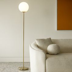 a white couch sitting next to a lamp in a living room