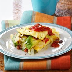 a white plate topped with an omelet covered in toppings