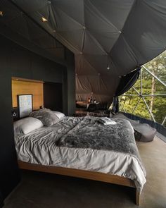 a large bed sitting under a tent next to a window with trees in the background