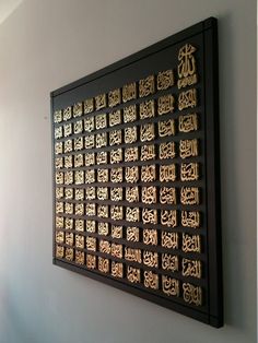 an intricately decorated wall hanging on the side of a building with arabic writing in gold and black