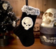 a crocheted stocking with a skull hanging from it's side on a table