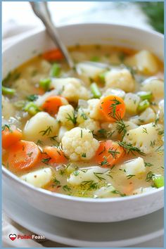 a bowl of soup with carrots, cauliflower and celery in it