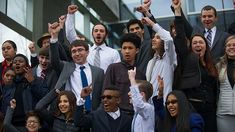 a group of people standing next to each other with their hands up in the air