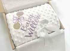 an open box with a white and purple blanket in it that says happy new year