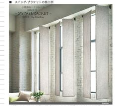 a living room with white brick walls and windows covered in roman blind shades, along with a couch