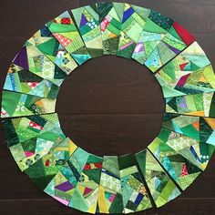 a wreath made out of green and multicolored paper on top of a wooden table