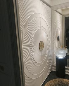 there is a white wall in the bathroom with circular designs on it and a round mirror