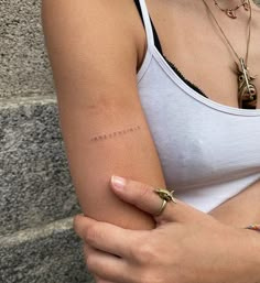 a woman wearing a white tank top holding her arm with the word love written on it