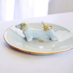 a white and gold plate with a dog figurine on it