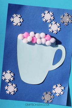 a paper cut out of a cup with snowflakes on it and pink pom - poms in the middle