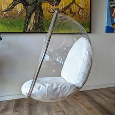 a swing chair hanging from the ceiling in a room with paintings on the wall and wood flooring