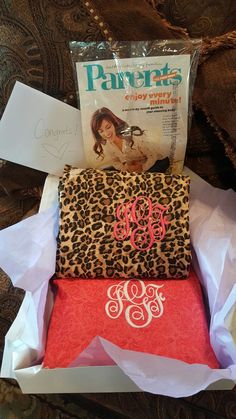 two leopard print wallets are sitting in a box on the bed, one has a monogrammed pocket