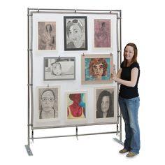 a woman standing in front of a wall with pictures hanging on it's sides