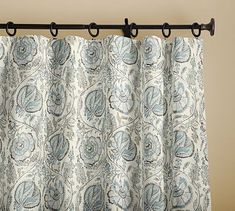 the curtain is hanging on the rod in front of the window with an ornate pattern