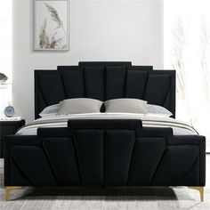 a bed with black headboard and pillows in a white room next to a window