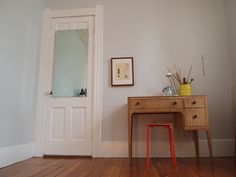 an empty room with a wooden desk and mirror on the wall next to a white door